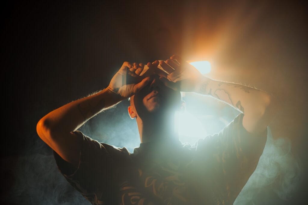 Dramatic portrait of a man standing in artistic lighting, creating a moody and introspective atmosphere.